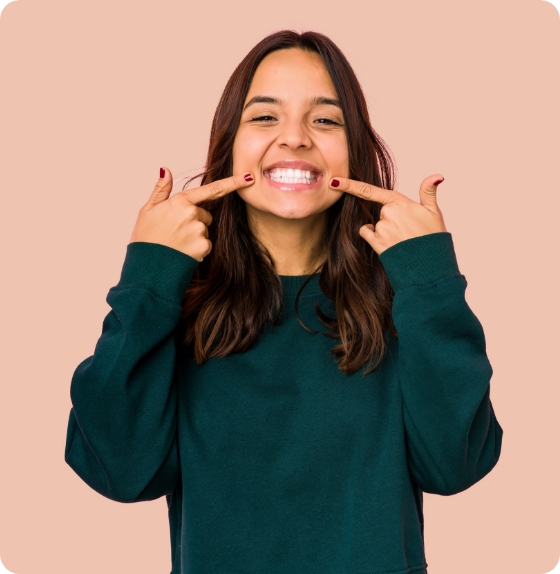 cheerful girl pointing to her white teeth