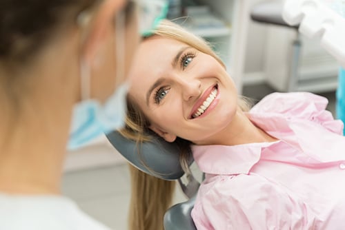 Young woman smiling and looking at dentist for wisdom teeth guidance at Dens Dental Studio in Chicago, IL.