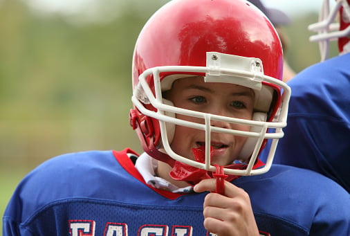 Young boy wearing football gear and a sports mouthguard from Dens Dental Studio in Chicago, IL.